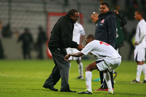 Photo: Former Caledonia AIA head coach Jamaal Shabazz (left) helps defender Kareem Joseph to his feet while assistant coach Rajeesh Latchoo looks on during CONCACAF Champions League action in 2013. (Courtesy Francisco Estrada/Jam MEDIA)