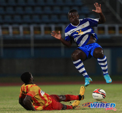 Photo: Can't touch this! Defence Force attacker Richard Roy (right) jumps out of the way of Point Fortin midfielder Bevon Bass' tackle during the 2013/14 Pro League season. (Courtesy Allan V Crane/Wired868)