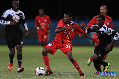 Photo: Caledonia AIA forward Dylon King (centre) holds off Central FC defender Elton John (right) while Jamal Jack looks on during the 2013/14 Pro League season. (Courtesy Allan V Crane/Wired868)