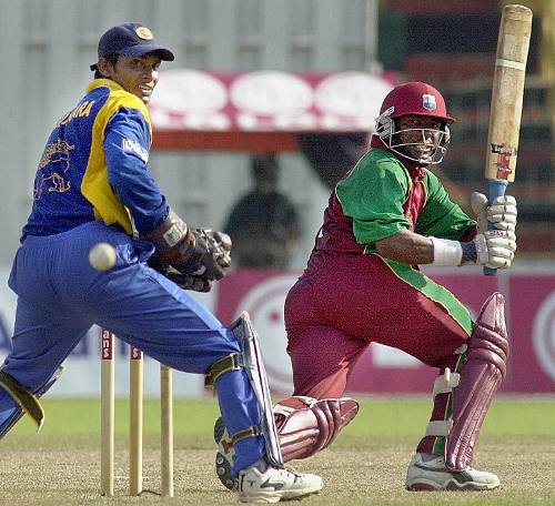 Photo: Former West Indies batsman Brian Lara sweeps to the boundary as Sri Lankan wicketkeeper Kumar Sangakkara looks on. (Copyright AFP 2014/Sena Vidanagama) 