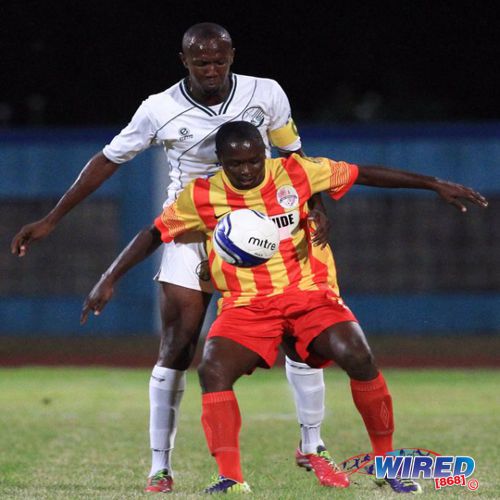 Photo: Former W Connection defender Daneil Cyrus (back) keeps a close watch on Point Fortin Civic attacker Sylvester Teesdale in the 2014 Lucozade Sport Goal Shield semifinal. (Courtesy Allan V Crane/Wired868)