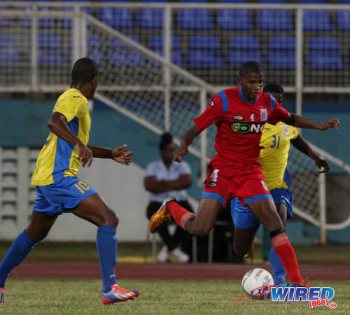 Photo: St Ann's Rangers utility player Jelani Peters (centre) looks for a teammate against Defence Force in a Pro League fixture. (Courtesy Allan V Crane/Wired868)