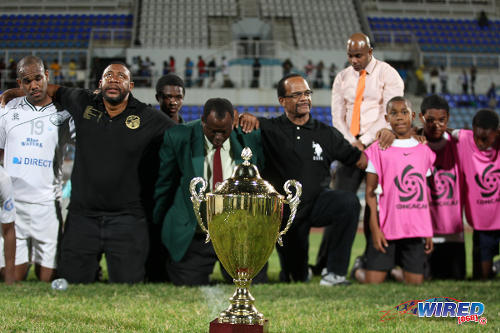 Photo: Former W Connection president David John Williams (second from left), coach Stuart Charles-Fevrier (centre) and defender Joel Russell (far left) say a prayer of thanks after securing the 2013/14 Pro League trophy at the Ato Boldon Stadium in Couva. (Courtesy Allan V Crane/Wired868)