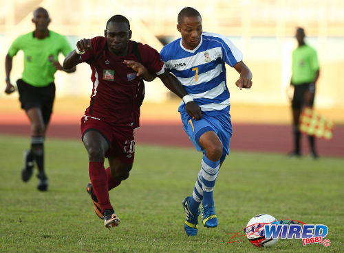 Photo: North East Stars striker Trevin Caesar (left) tries to burst past Defence Force attacker Balondemu Julius during the 2013/14 Pro League season. (Courtesy Allan V Crane/Wired868)