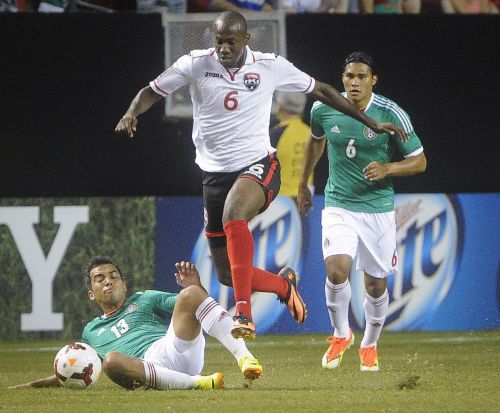 Photo: Trinidad and Tobago's Daneil Cyrus (centre) hurdles Mexico player Adrian Aldrete (left) while his teammate Carlos Pena looks on in the 2013 Gold Cup quarterfinal at the Georgia Dome in Atlanta. (Copyright AFP 2014/ John Amis)