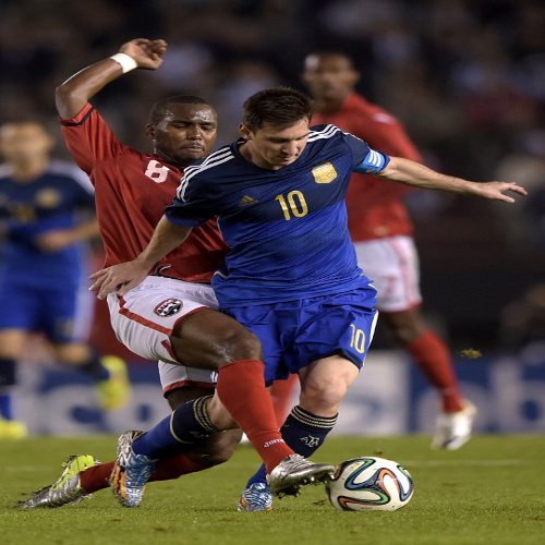 Photo: Argentina captain Lionel Messi (right) is tackled by Trinidad and Tobago midfielder Khaleem Hyland during their international fixture in Buenos Aires on 4 June 2014. (Copyright AFP 2014/ Juan Mabromata)