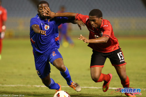 Photo: Trinidad and Tobago winger Aikim Andrews (right) forces his way past Haiti defender Stephane Lambese during the 2014 Under-20 Caribbean Cup. (Courtesy Allan V Crane/Wired868)