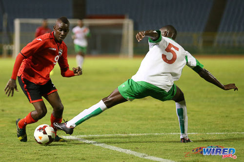 Photo: Trinidad and Tobago striker Kadeem Corbin (left) eludes Suriname defender Nigel Zandveld during an 2014 Under-20 Caribbean Cup fixture. (Courtesy Allan V Crane/Wired868)