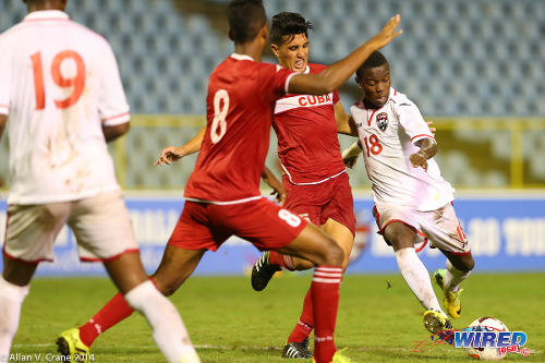 Photo: Trinidad and Tobago National Under-20 midfielder Jabari Mitchell (right) tries to squeeze a shot past two Cuban defenders during the 2014 Caribbean Cup. (Courtesy Allan V Crane/Wired868)