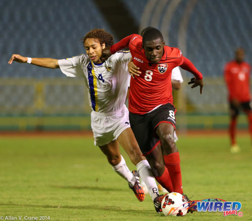 Photo: Trinidad and Tobago midfielder Neveal Hackshaw (right) holds off Curaçao defender Luivienno Statia during the 2014 U-20 Caribbean Cup. (Courtesy Allan V Crane/Wired868)