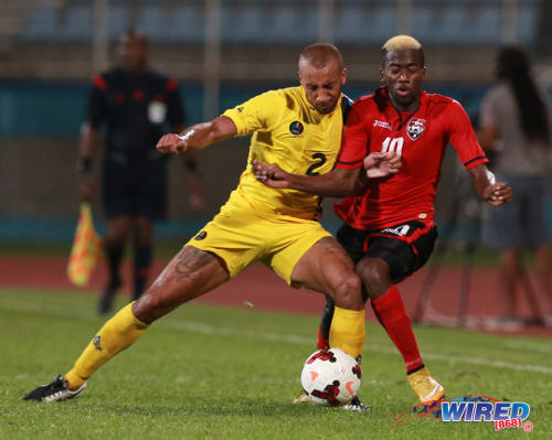 Photo: Antigua and Barbuda midfielder Joshua Parker (left) barges into Trinidad and Tobago attacker Kevin Molino during 2014 Caribbean Cup qualifying action. Molino will miss the 2015 CONCACAF Gold Cup through injury. (Courtesy Allan V Crane/Wired868)