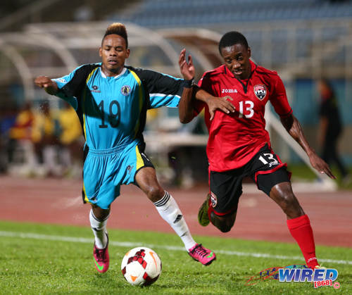 Photo: Trinidad and Tobago winger Cordell Cato (right) motors past St Lucia right back Erick Gabriel during the 2014 Caribbean Cup qualifying series. (Courtesy Allan V Crane/Wired868)