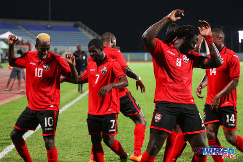 Photo: Trinidad and Tobago scorer Kevin Molino (far left) leads teammates Hughtun Hector (second from left) and captain Kenwyne Jones (second from right) in a goal dance during 2014 Caribbean Cup qualifying action against Antigua and Barbuda. (Courtesy Allan V Crane/Wired868)