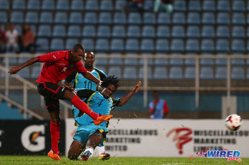 Photo: Trinidad and Tobago playmaker Ataulla Guerra (left) drives his shot past St Lucia player Perral Williams during 2014 Caribbean Cup qualifying action at the Ato Boldon Stadium, Couva. (Courtesy Allan V Crane/Wired868)