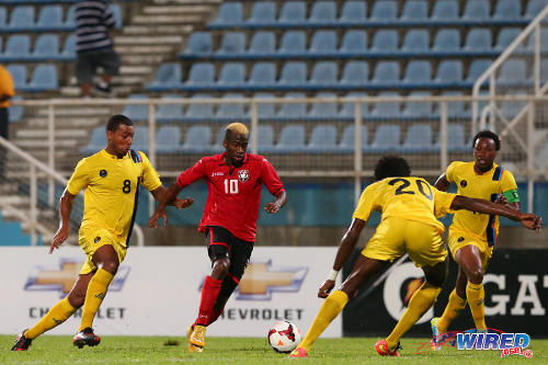 Photo: Trinidad and Tobago midfielder Kevin Molino (second from left) runs at Antigua and Barbuda players (from left) Keiran Murtagh, Akeem Thomas and Quinton Griffith during 2014 Caribbean Cup qualifying action. (Courtesy Allan V Crane/Wired868)