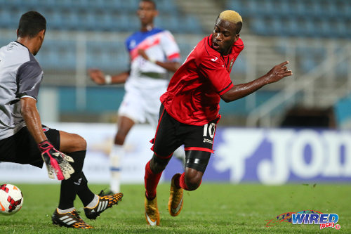 Photo: Trinidad and Tobago attacker Kevin Molino (right) flicks his third goal past Dominican Republic goalkeeper Miguel Lloyd during the 2014 Caribbean Cup qualifying round. (Courtesy Allan V Crane/Wired868)