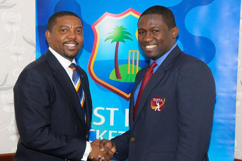 Photo: West Indies Players Association (WIPA) president Wavell Hinds (right) and West Indies Cricket Board (WICB) president Dave Cameron shake hands over the players' controversial CBA/MOU in September 2014. (Courtesy WIPA)