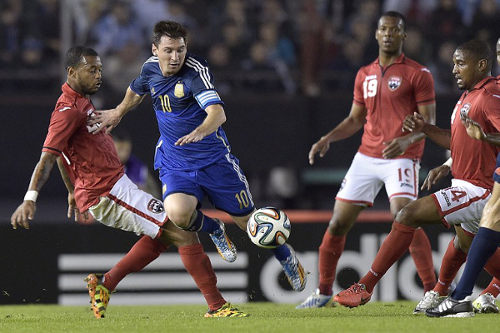 Photo: Argentina captain and superstar Lionel Messi (centre) dribbles between Trinidad and Tobago players Lester Peltier (far left), Andre Boucaud (far right) and Carlyle Mitchell during an international friendly in Buenos Aires on 4 June 2014. Argentina won 3-0. (Copyright AFP 2014/Daniel Garcia)