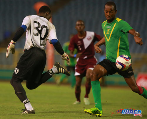 Photo: Mucurapo East Secondary goalkeeper Aaron Enill (left) loses possession to St Benedict's College forward Meriba Des Cartes (right) in the 2014 National Intercol final. (Courtesy Allan V Crane/Wired868)