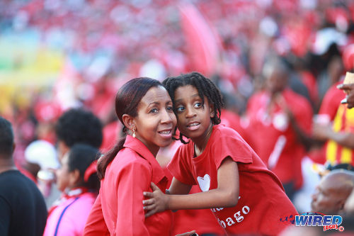 Photo: An adult and child support the "Women Soca Warriors" during their FIFA Play Off second leg clash against Ecuador in Port of Spain on 2 December 2014. (Courtesy Allan V Crane/Wired868)