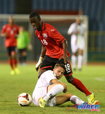 Photo: Trinidad and Tobago National Under-20 midfielder Jabari Mitchell plays the ball around a Curacao player during the 2014 Caribbean Cup. (Courtesy Allan V Crane/Wired868)