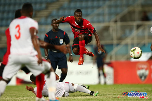 Photo: Trinidad and Tobago and Orlando City playmaker Kevin Molino (right) hurdles a tackle against Panama during an international friendly in March 2015. (Courtesy Allan V Crane/Wired868)