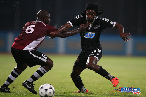 Photo: Central FC substitute Jason Marcano (right) takes on North East Stars substitute Jeromie Williams during 2014/15 Pro League action. (Courtesy Allan V Crane/Wired868)