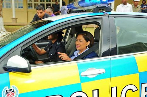 Photo: Prime Minister Kamla Persad-Bissessar takes a lift in a police car. (Courtesy UNCTT.org)