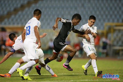 Photo: Central FC striker Willis Plaza (centre) charges through the centre of the Comunicaciones defence during 2015 CONCACAF Champions League action. (Courtesy Allan V Crane/Wired868)