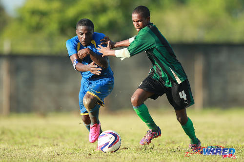 Photo: Shiva Boys Hindu College winger Quinn Rodney (left) tries to escape from a Carapichaima East Secondary defender during a 2015 SSFL contest. (Courtesy Allan V Crane/Wired868)