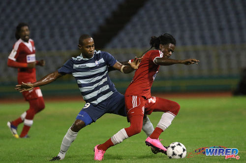 Photo: Central FC winger Jason Marcano (right) tries to elude Police FC forward Makesi Lewis during 2015 First Citizens Cup quarterfinal action at the Hasely Crawford Stadium. (Courtesy Chevaughn Christopher/Wired868)