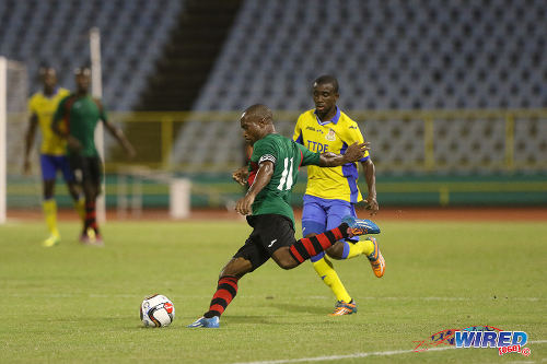 Photo: San Juan Jabloteh captain Damian Williams (foreground) prepares to drive a cross into the opposing penalty area during 2015 First Citizens Cup action against Defence Force. (Courtesy Chevaughn Christopher/Wired868)