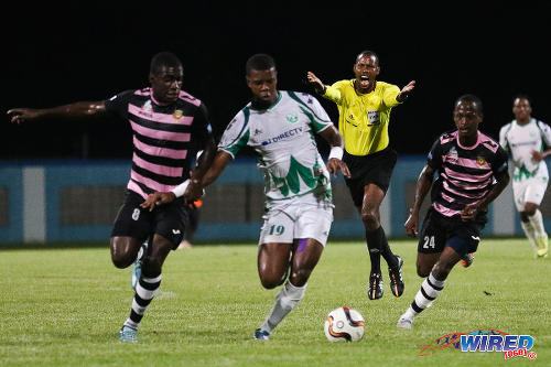 Photo: Referee Rodphin Harris (background) waves play on as W Connection striker Dwight Quintero (centre) tries to keep possession from North East Stars players Neveal Hackshaw (left) and Adrian Noel during 2015 Toyota Classic quarterfinal action. (Courtesy Chevaughn Christopher/Wired868)