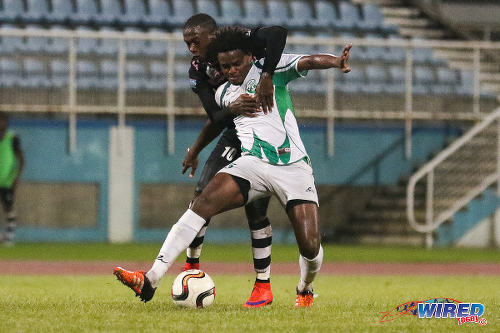 Photo: W Connection defender Triston Hodge (foreground) holds off North East Stars forward Keron Cummings during 2015 Toyota Classic quarterfinal action. (Courtesy Chevaughn Christopher/Wired868)