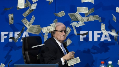 Photo: My money ha ha... FIFA president Sepp Blatter falls victim to a prank during a press conference. (Copyright CBC)