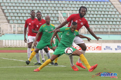 Photo: Guaya United striker Carlon Hughes (foreground) tries to shake off giant Petrotrin Palo Seco defender Wayne Huyghue (right) in the 2015 CNG NSL Knock Out final while Guaya captain Ryan Stewart (centre) looks on. (Courtesy Chevaughn Christopher/Wired868)