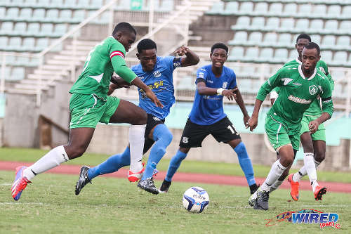 Photo: St Augustine Secondary captain Joshua Marshall (left) tries to nick possession away from Naparima College attacker Akinola Gregory (second from left) while Isaiah Hudson (centre) and Ainsworth Grant look on during 2015 National Intercol semifinals. (Courtesy Chevaughn Christopher/Wired868)