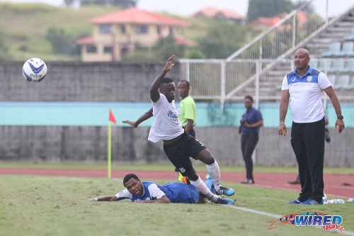 Photo: Naparima College left back Khris Stroud (centre) is taken out by a Presentation College (San Fernando) player while Pres coach Shawn Cooper (right) looks on during the the 2015 South Intercol final in Marabella. (Courtesy Chevaughn Christopher/Wired868)