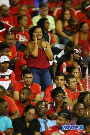 Photo: A female Trinidad and Tobago fan (centre) phones it in during a lull in action at the 2018 World Cup qualifier between Trinidad and Tobago and the United States on 17 November 2015. (Courtesy Allan V Crane/Wired868)