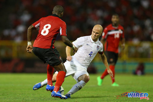 Photo: Trinidad and Tobago midfielder Khaleem Hyland (left) rolls the ball through the legs of United Staes captain Michael Bradley during 2018 World Cup qualifying action at the Hasely Crawford Stadium. (Courtesy Allan V Crane/Wired868)