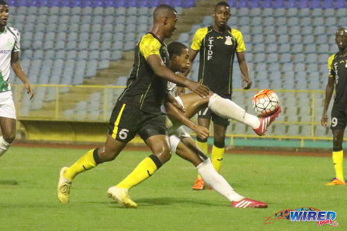 Photo: W Connection midfielder Briel Thomas (centre) controls the ball under pressure from Defence Force player Rodell Elcock in the 2015 Toyota Classic final. (Courtesy Chevaughn Christopher/Wired868)