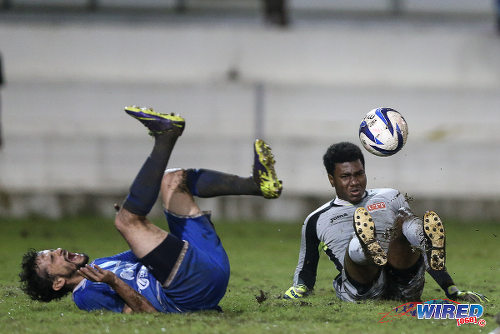 Photo: UTT goalkeeper Perry Martin (right) takes out QPCC attacker Benedict Barrett during 2015 CNG NSL Championship Division action at UTT Grounds, Arima.  (Courtesy Allan V Crane/CA-images/Wired868)