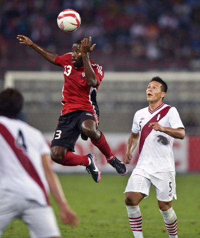 Photo: Trinidad and Tobago striker Cornell Glen (centre) beats Peru's Alfredo Rojas (right) to the ball during friendly international action in 2013. (Copyright AFP 2015/Ernesto Benavides)