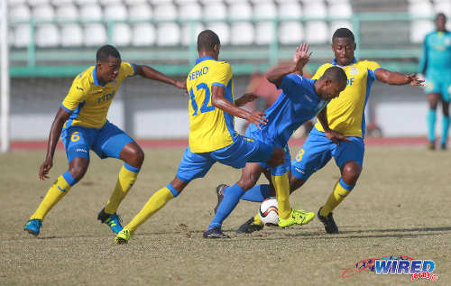 Photo: Police FC winger Christon Thomas (second from right) tries to elude Defence Force players Sean Narcis (right), Jemel Sebro (centre) and Rodell Elcock during 2015/16 Pro League action in Malabar. (Courtesy Nicholas Bhajan/Wired868)