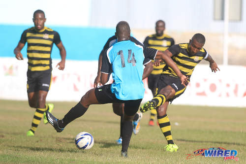 Photo: Defence Force captain and midfielder Christopher Durity (right) shoots past WASA defender Christopher Mitchell during CNG National Super League Premiership Division action in St Joseph. (Courtesy Nicholas Bhajan/Wired868)