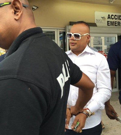 Photo: "Is ranking ting with allyuh yes, TV6!" CNC3 Crime Watch host Ian Alleyne (right) is taken for medical treatment by a policeman. (Copyright CNC3)