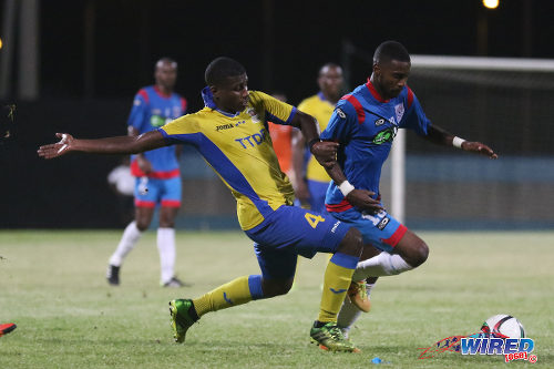 Photo: St Ann's Rangers captain Johan Peltier (right) tries to escape from Defence Force midfielder Dave Long during TT Pro League action at the Ato Boldon Stadium on 1 March 2016. (Courtesy Chevaughn Christopher/Wired868)