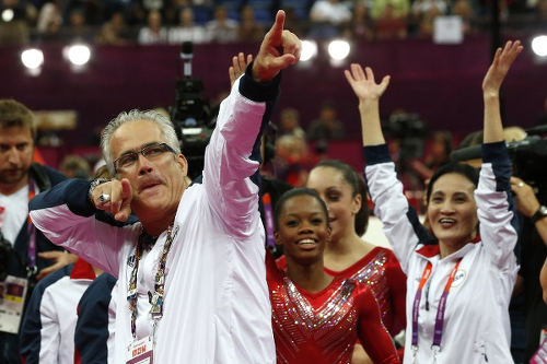 Photo: US women gymnastics team’s coach John Geddert celebrates with the rest of the team after the US won gold in the artistic gymnastics event of the London Olympic Games on 31 July 2012 at the 02 North Greenwich Arena in London. (Copyright AFP 2016/Thomas Coex)