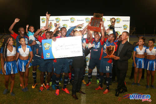 Photo: Morvant Caledonia United players celebrate with the winning trophy and cheque after defeated W Connection in the Lucozade Sport Goal Shield final on 21 April 2016. Looking on (far right) is Pro League CEO Dexter Skeene. (Courtesy Nicholas Bhajan/Wired868)