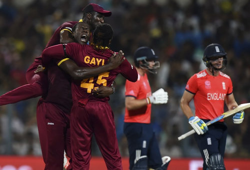 Photo: West Indies bowler Carlos Brathwaite (second from left) celebrates with captain Darren Sammy (top) and Chris Gayle after the wicket of England's Jos Buttler (far right) during the World T20 cricket tournament final match at The Eden Gardens Cricket Stadium in Kolkata on 3 April 2016. Carlos Brathwaite sensationally hit four successive sixes off Ben Stokes in the last over as the West Indies stunned England by four wickets to win the World Twenty20 title. (Copyright AFP2016/Dibyangshu Sarkar)